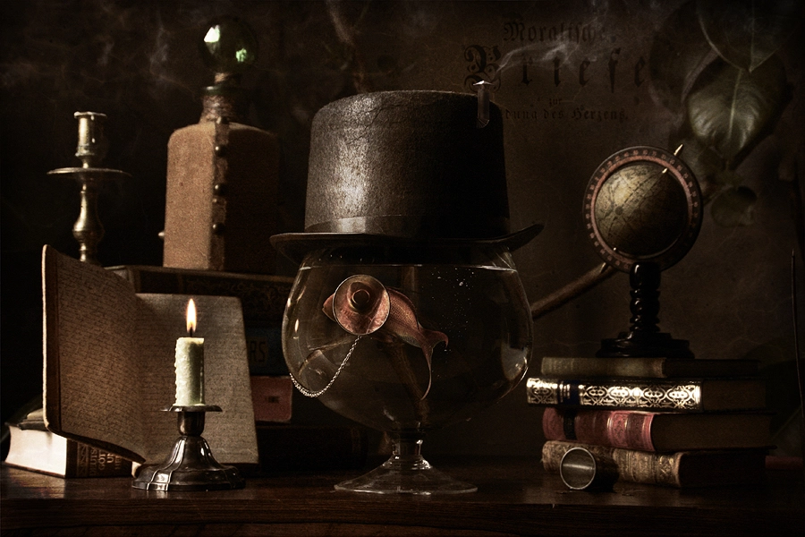 Surreal still life of a goldfish in a bowl reading a book with candle light